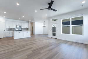 Kitchen with ceiling fan with notable chandelier, hanging light fixtures, white cabinets, and stainless steel appliances