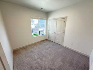 Unfurnished bedroom featuring a closet and light colored carpet