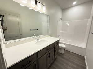 Full bathroom featuring hardwood / wood-style floors, vanity, toilet, and shower / bathtub combination