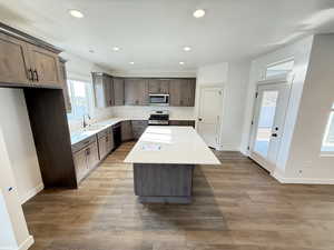 Kitchen featuring a kitchen island, wood-type flooring, sink, and stainless steel appliances