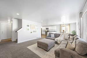 Living room with sink, a notable chandelier, light colored carpet, and a textured ceiling