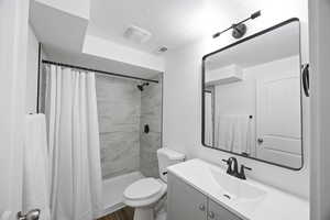 Bathroom with tile flooring, shower, vanity, and toilet