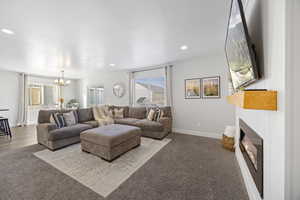 Living room featuring a wealth of natural light, light carpet, a textured ceiling, and a notable chandelier