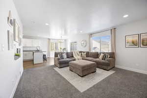 Living room featuring a textured ceiling, light colored carpet, an inviting chandelier, and sink