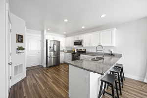 Kitchen featuring sink, stainless steel appliances, kitchen peninsula, a breakfast bar, walk-in pantry, and white cabinets