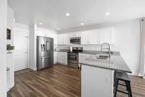 Kitchen with white cabinets, a breakfast bar, kitchen peninsula, and appliances with stainless steel finishes