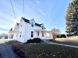 View of front of property featuring a balcony, a porch, and a front yard