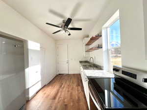 Kitchen featuring sink, light hardwood / wood-style flooring, electric range, light stone countertops, and white cabinetry