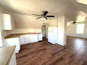 Kitchen with white appliances, dark wood-type flooring, sink, white cabinets.