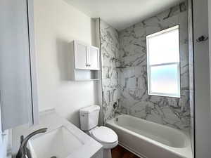 Full bathroom main level featuring vanity, a healthy amount of sunlight, tiled shower / bath combo, and toilet