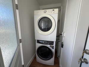 Main Floor Laundry room featuring stacked washer / drying machine and dark hardwood / wood-style flooring