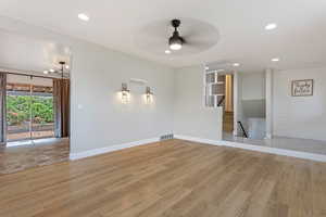 Living room featuring light wood-type flooring, ceiling fan, and wood walls