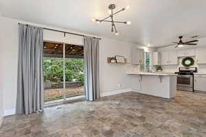 Kitchen with gray cabinetry, plenty of natural light, a breakfast bar area, and stainless steel range oven