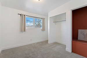 Unfurnished bedroom with light carpet and a closet