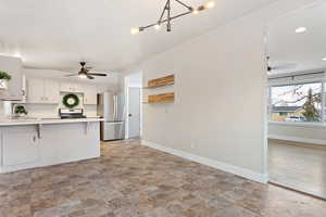 Kitchen witha breakfast bar, sink, kitchen peninsula, appliances with stainless steel finishes, and white cabinetry