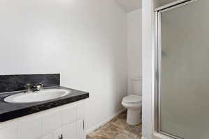 Bathroom featuring decorative backsplash, toilet, a shower with door, and sink