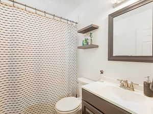 Bathroom featuring a shower with shower curtain, vanity, and toilet