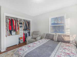 Bedroom with dark hardwood / wood-style floors and a closet