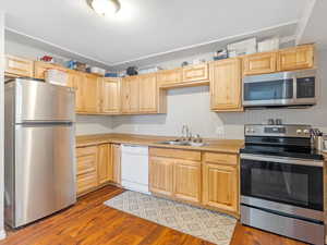 Kitchen featuring light brown cabinetry, sink, appliances with stainless steel finishes, and light hardwood / wood-style flooring