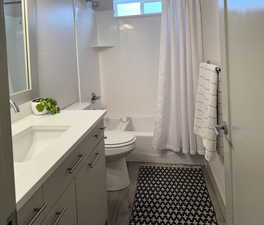 Full bathroom with hardwood / wood-style flooring, vanity, toilet, and shower / tub combo with curtain