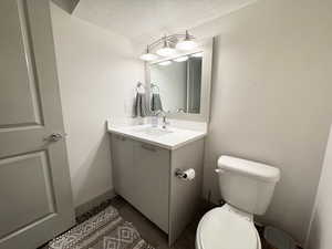 Bathroom with vanity, toilet, wood-type flooring, and a textured ceiling