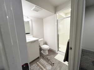 Bathroom with walk in shower, wood-type flooring, a textured ceiling, toilet, and vanity