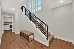 Stairs featuring hardwood / wood-style flooring and washer and clothes dryer