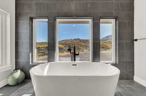 Bathroom featuring a mountain view, a bath, and tile walls