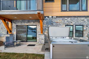 View of patio with a covered hot tub and a balcony