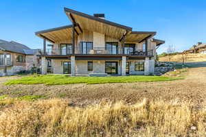 Rear view of property with a yard and a balcony