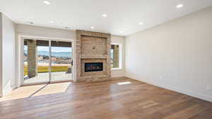 Unfurnished living room with a mountain view, a stone fireplace, and light hardwood / wood-style flooring