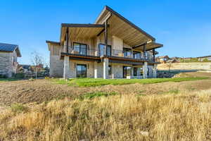 Back of house with a lawn and a balcony