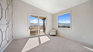 Unfurnished room with a mountain view, light carpet, and vaulted ceiling