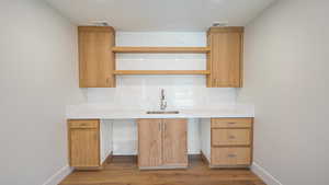 Kitchen featuring decorative backsplash, light wood-type flooring, and sink