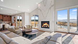 Living room with a mountain view, a high end fireplace, wood-type flooring, and vaulted ceiling