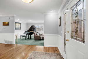 Entryway featuring crown molding and wood-type flooring