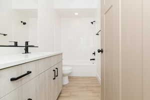 ADU Full bathroom with shower / bathing tub combination, wood-type flooring, vanity, and toilet