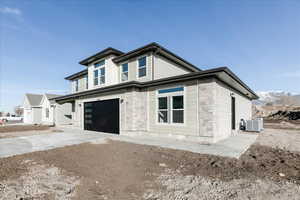 View of front of home featuring a garage and cooling unit