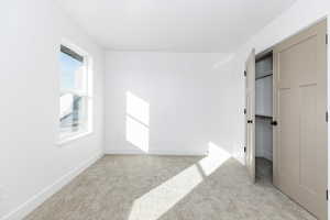 Unfurnished bedroom with light carpet and a closet