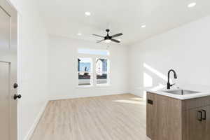 Bar featuring light hardwood / wood-style floors, ceiling fan, and sink