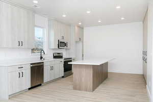 Kitchen featuring a kitchen island, light wood-type flooring, sink, and appliances with stainless steel finishes