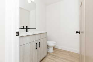 Bathroom featuring hardwood / wood-style floors, vanity, and toilet