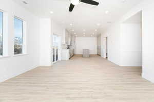 Empty room featuring light wood-type flooring, ceiling fan, and sink