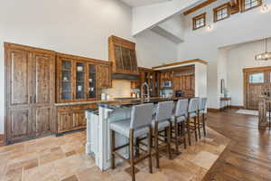 Kitchen with a breakfast bar area, a kitchen island with sink, a high ceiling, and light wood-type flooring