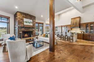 Living room with high vaulted ceiling, hardwood / wood-style flooring, and a stone fireplace