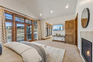 Carpeted bedroom featuring a fireplace, access to outside, high vaulted ceiling, and multiple windows