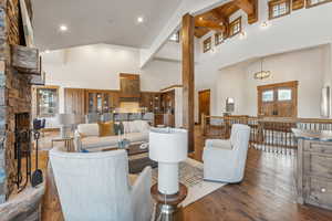 Living room with dark wood-type flooring, beamed ceiling, high vaulted ceiling, a notable chandelier, and a fireplace