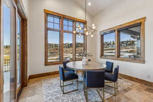 Dining area featuring a wealth of natural light, vaulted ceiling, and an inviting chandelier