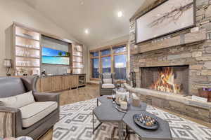 Living room with a fireplace, vaulted ceiling, and light hardwood / wood-style flooring