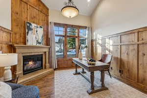 Office area featuring hardwood / wood-style floors, high vaulted ceiling, and wooden walls